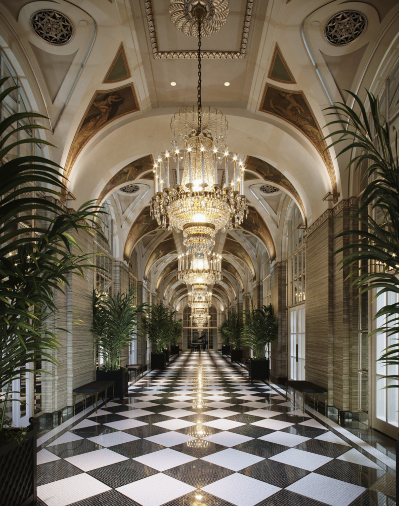 a long hallway with chandeliers and plants